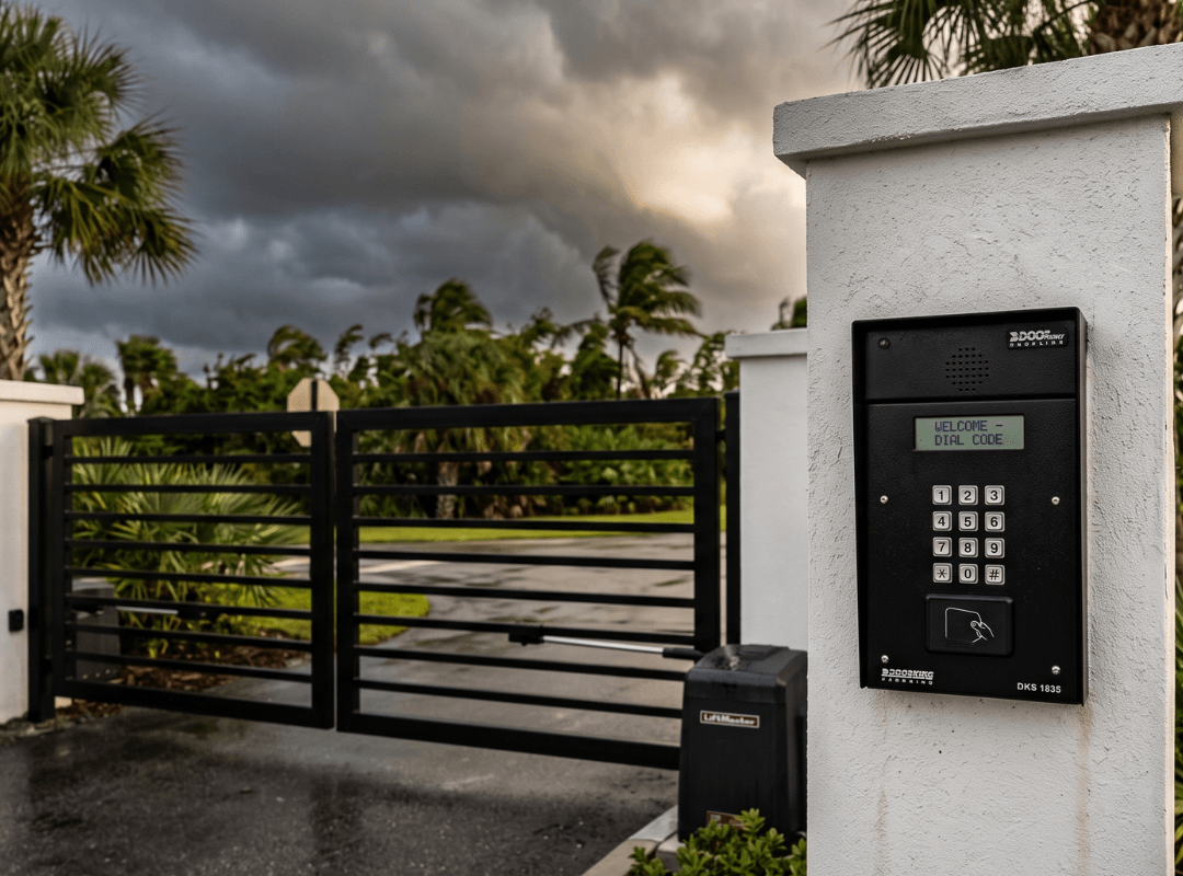 HOA Gate Access Control — Hurricane Season Preparedness | Sarasota Gate & Access DoorKing DKS 1835 keypad and LiftMaster gate operator at a Sarasota HOA community entry with storm clouds building overhead during Florida hurricane season
