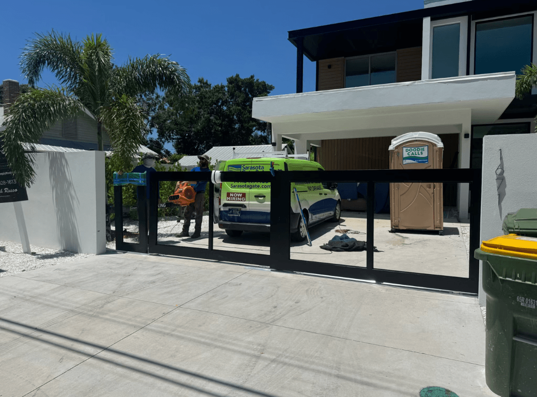 Residential Driveway Gate Installation — Fort Myers, FL | Sarasota Gate & Access Sarasota Gate & Access technicians installing a modern aluminum sliding driveway gate at a luxury residential property in Fort Myers, FL