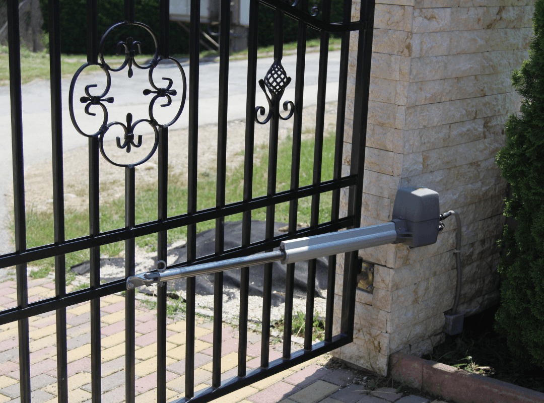 Automated swing gate operator with linear actuator arm mounted on an ornamental iron residential gate — the type of gate system serviced by Sarasota Gate & Access in Fort Myers, FL