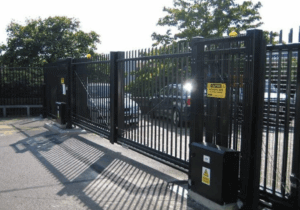 Heavy-duty commercial automated sliding gate with gate operator and caution signage installed at a commercial property — the type of commercial gate installation Sarasota Gate & Access delivers for business owners and property managers