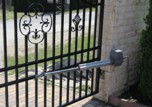 Automated swing gate operator with linear actuator arm mounted on an ornamental iron residential gate — the type of gate system serviced by Sarasota Gate & Access in Fort Myers, FL
